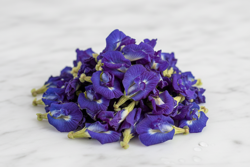 Purple butterfly pea flowers on a white marble surface